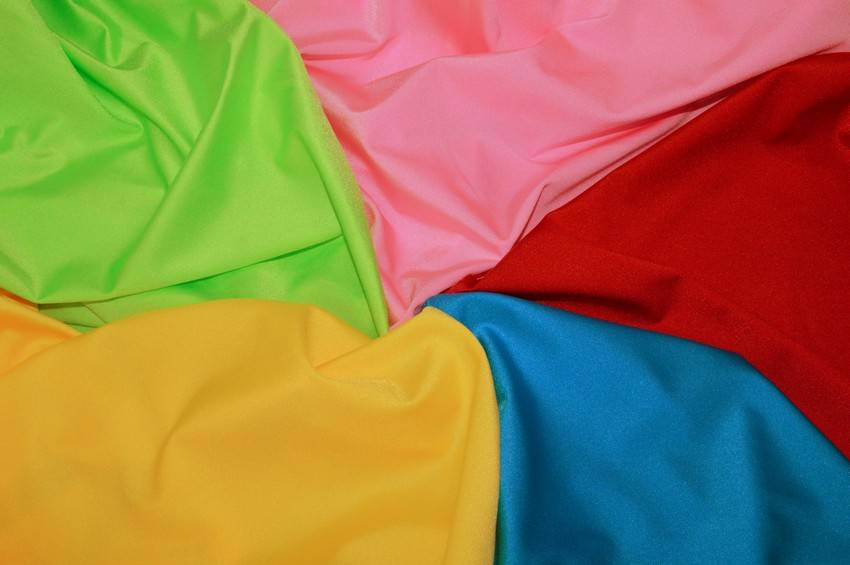 Dettaglio ravvicinato di tessuto lycra lucida elastica in vari colori brillanti