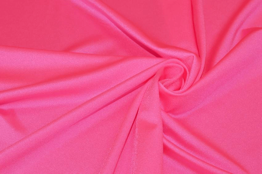Tessuto in lycra lucida fucsia fluo arrotolata, ideale per cucito creativo.
